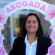 La foto muestra a Pia Ricchieri sosteniendo un cartel con su nombre y que dice abogada. Ella sonríe y el cartel tiene flores rosadas.